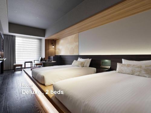 a hotel room with two beds and a desk at Mitsui Garden Hotel Ginza-gochome in Tokyo