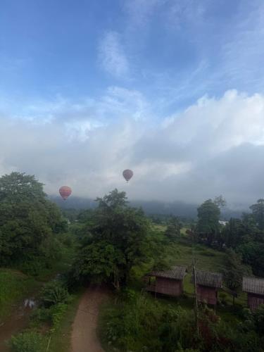 two hot air balloons flying over a dirt road at The Big Brother Mouse Hostel in Vang Vieng