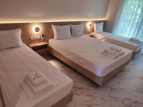 two beds in a hotel room with towels on them at Estelle Hotel in Gerakini