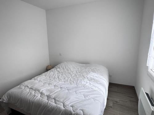 a white bed in a corner of a room at Ideal pour un couple in Saint-Georges-dʼOléron