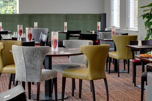 a dining room with tables and yellow chairs at Best Western Appleby Park Hotel in Tamworth