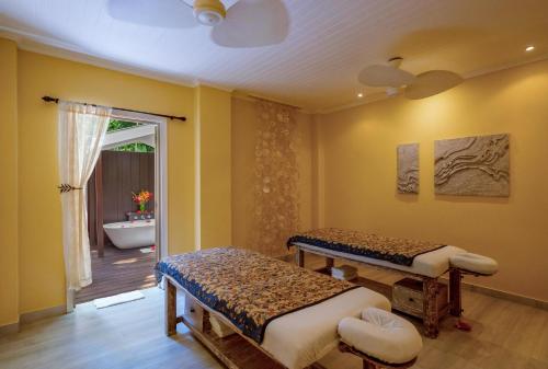 a room with two beds and a bathroom with a tub at Paradise Sun Hotel Seychelles in Baie Sainte Anne