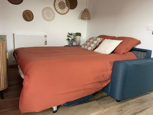 a bedroom with a large orange bed with a blue chair at L échappée bêle in Le Val-Saint-Père