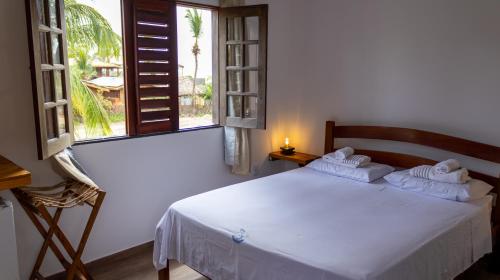 a bedroom with a white bed and a window at Pousada Ventos do Guajiru-Casa de Kitesurfistas in Itarema