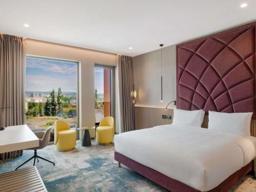 a hotel room with a bed and a large window at Mercure Oradea in Oradea