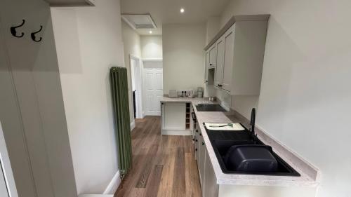 a kitchen with white cabinets and a black sink at Holt Hall - First Floor Apartment in Matlock