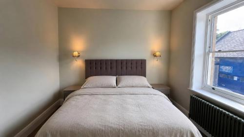 a bed in a bedroom with a window at Holt Hall - First Floor Apartment in Matlock