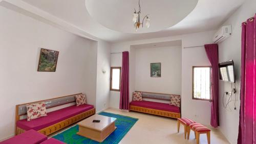 a living room with two beds and pink curtains at Villa Sunset résidence Djerba in Djerba