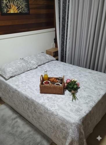 a basket of fruit and a basket of flowers on a bed at Chalé Vale Carahá Hortensia in Gramado