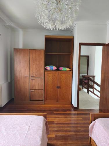 a bedroom with a bed and a cabinet and a chandelier at Casa Airiños do monte in Cangas de Morrazo