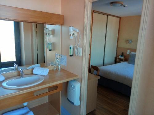 a bathroom with a sink and a bed at Hotel Restaurant La Clairiere in Chambon-sur-Dolore