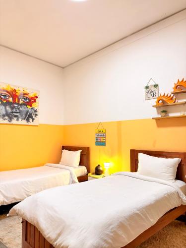 two beds in a room with yellow walls at Cozy & Secure 1BR Apartment in Central Luanda in Luanda