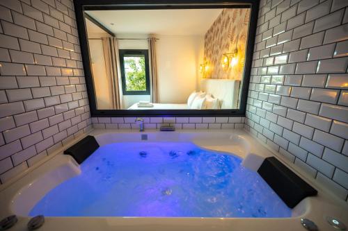 a large blue tub in a bathroom with a mirror at Le Maleville - Appartements de Standing in Périgueux