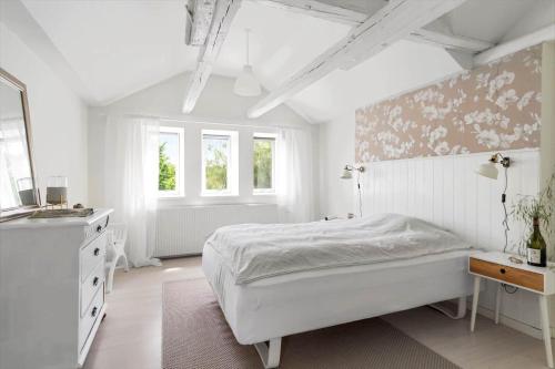 a white bedroom with a bed and a dresser and windows at 20335-Samso-Marsk-Stigs-vej-4 in Tranebjerg