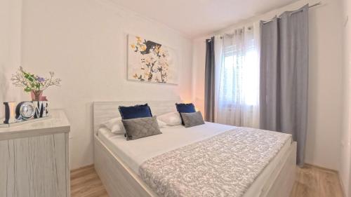 a white bedroom with a white bed with blue pillows at CASA di NATALIA, Spacious 2BR Apartment for 6 near Beach ,Free Parking in Kaštela