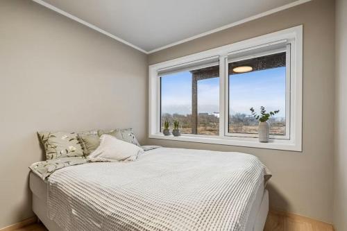 a white bedroom with a bed and a window at Apartment Lofoten, Leknes in Leknes