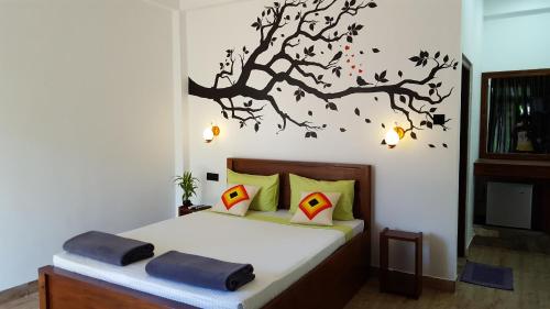 ein Schlafzimmer mit einem Bett mit einem Baumbild an der Wand in der Unterkunft Lavendra Paradise in Ella
