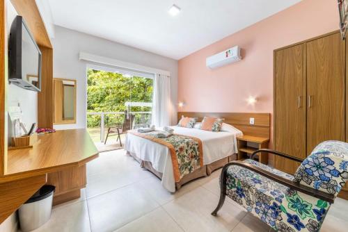 a bedroom with a bed and a desk and a window at Pousada Cantinho da Praia in Paraty