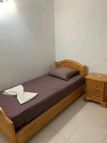 a bed with a wooden frame and a night stand at Villa Syrine Djerba in Al Ḩaddādah