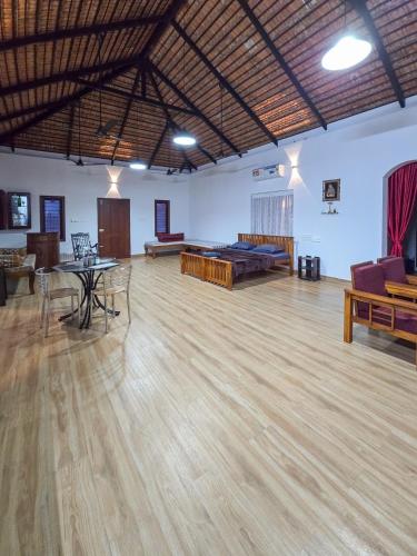 a large room with a wooden floor with tables and chairs at Benny's Abode by UrbanEase Properties in Mangalore