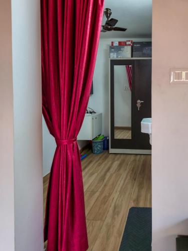 a red curtain in the corner of a room at Benny's Abode by UrbanEase Properties in Mangalore