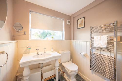 a bathroom with a sink and a toilet and a window at Fishermans Cottage, Aldeburgh in Aldeburgh