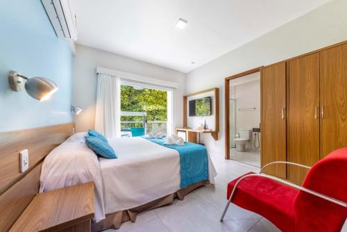 a bedroom with a bed and a red chair at Pousada Cantinho da Praia in Paraty