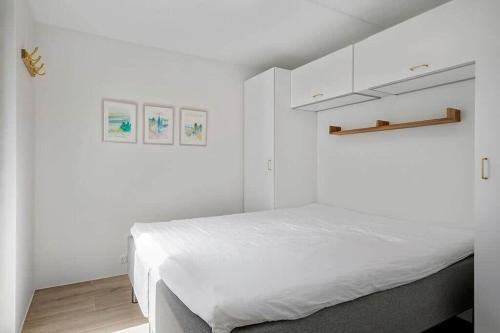 a white bedroom with a bed and white cabinets at BL1001-Blokhus-Ferren-95 in Blokhus