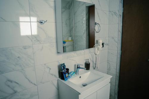 a white bathroom with a sink and a mirror at Village Bliss in Kardamaina