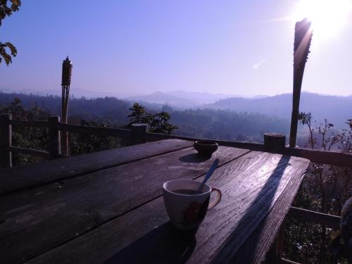 a coffee cup sitting on a wooden table with a view at Khunyuam Resort in Ban Khun Yuam