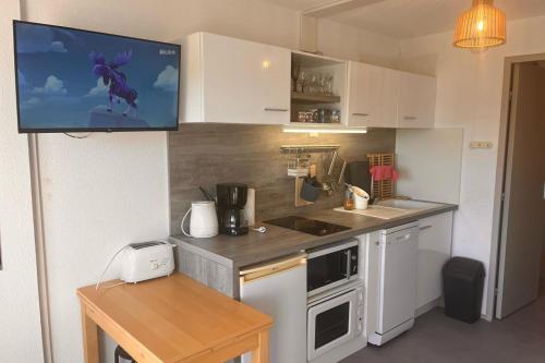 a kitchen with a tv hanging on the wall at Pool and beach studio in Quiberon