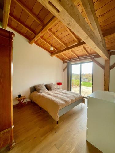 a bedroom with a bed and a large window at Gîte de groupe et charmant cottage L'Agnel in Domaize