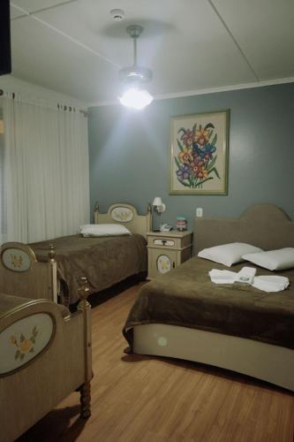 a hotel room with two beds and a lamp at Nova Vicenza Hotel in Farroupilha