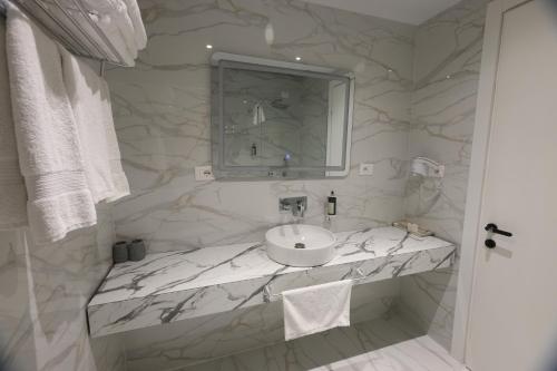 a white bathroom with a sink and a mirror at Metro Hotel Terminal in Tirana