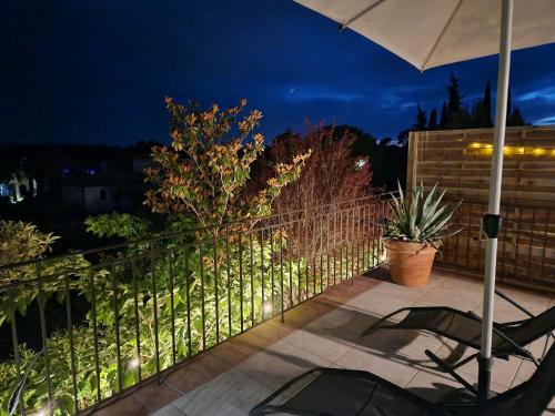 ein Balkon mit Stühlen und einem Sonnenschirm bei Nacht in der Unterkunft Maison Corbert in Siran