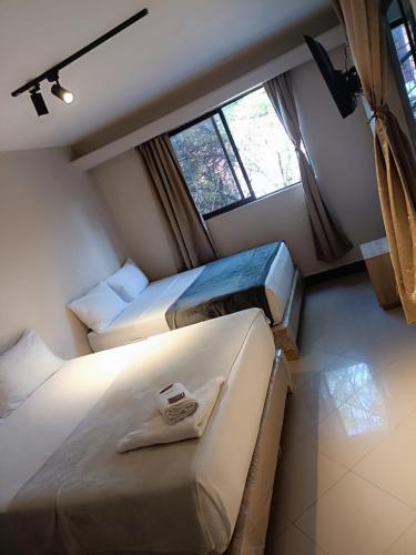 a bedroom with three beds and a window at Hotel Golden 70 in Medellín
