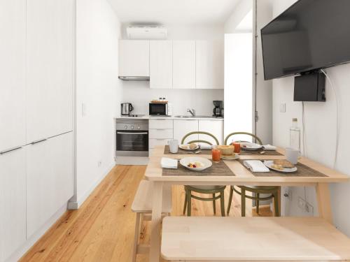 a white kitchen with a wooden table and chairs at LSA Castelo S Jorge by Numa in Lisbon