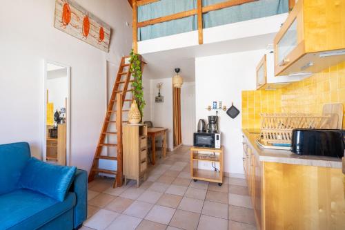 a living room with a blue couch and a kitchen at Le Refuge des Embruns - Port & plages - 4 pers - Tout confort et équipé in LʼHerbaudière