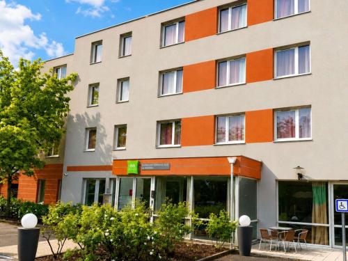an orange and white building with tables in front of it at ibis Styles Clermont Ferrand Sud La Pardieu in Clermont-Ferrand
