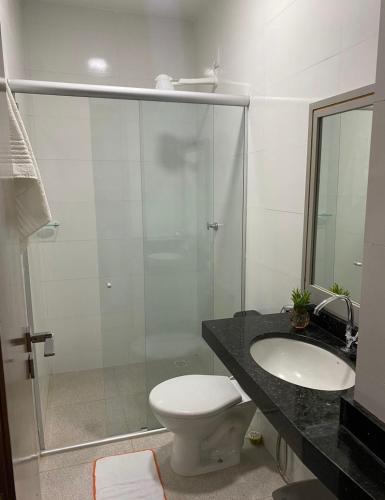 a bathroom with a shower and a toilet and a sink at Hotel Caeté in Bragança