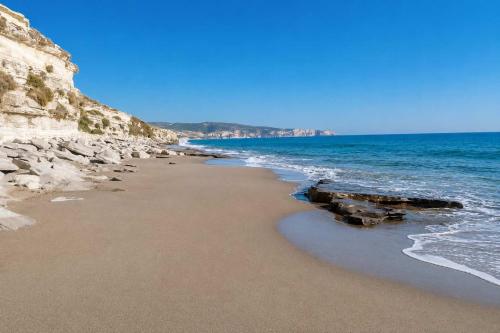 a beach with rocks and the ocean on a sunny day at Villa Maria Christina with Private Pool in Crete in Skoúrvoula