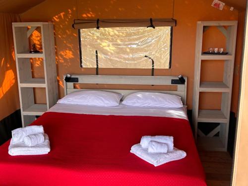 a bedroom with a red bed with two white towels at GLAMPING by SUNBEAM in Leporano Marina