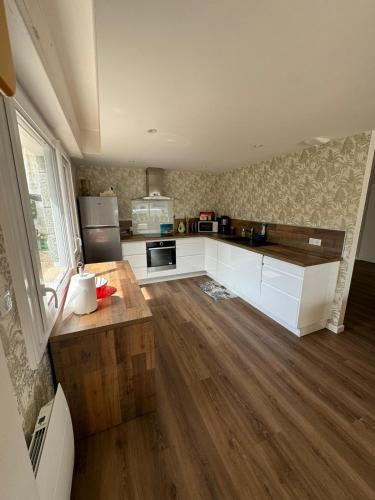 a kitchen with white cabinets and a wooden floor at Maison proche centre ville in Quiberon