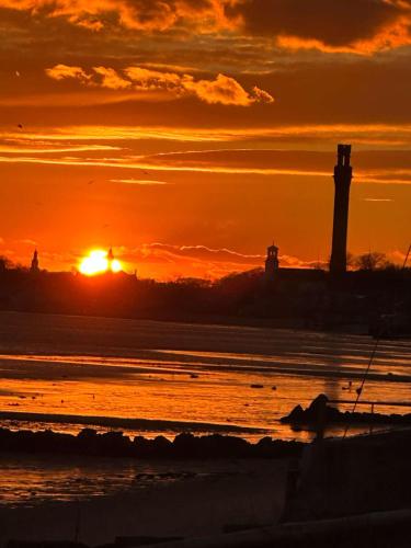 a sunset over a beach with two lighthouses at Moon Tide - Bayside Beach Access & Parking in Provincetown