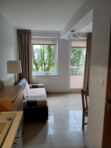 a living room with a couch and two windows at Apartament 112 Mielno in Mielno