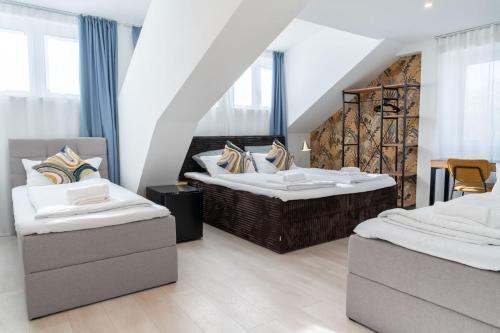 two beds in a room with two chairs at Villa Vaicun - Boutique Rooms in Lörrach