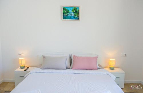 a bedroom with a white bed with two lamps at Kuća za odmor Veronika in Klobuk