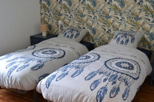 two beds in a bedroom with blue and white covers at Gîte les Grands Orangers in Melle