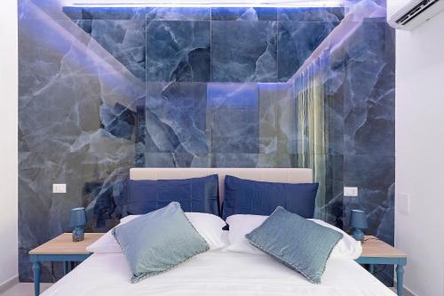 a bed with two pillows in front of a wall at Suite Horizon Marine in San Vito lo Capo