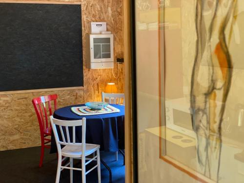 a room with a table with chairs and a chalkboard at La Cabane des Bains in Marciac